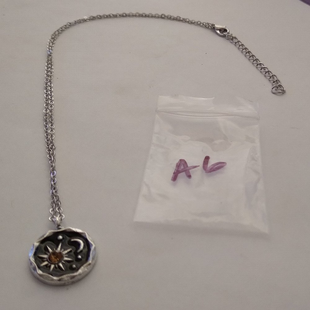 The silver and black moon and sun pendant with simulated yellow topaz